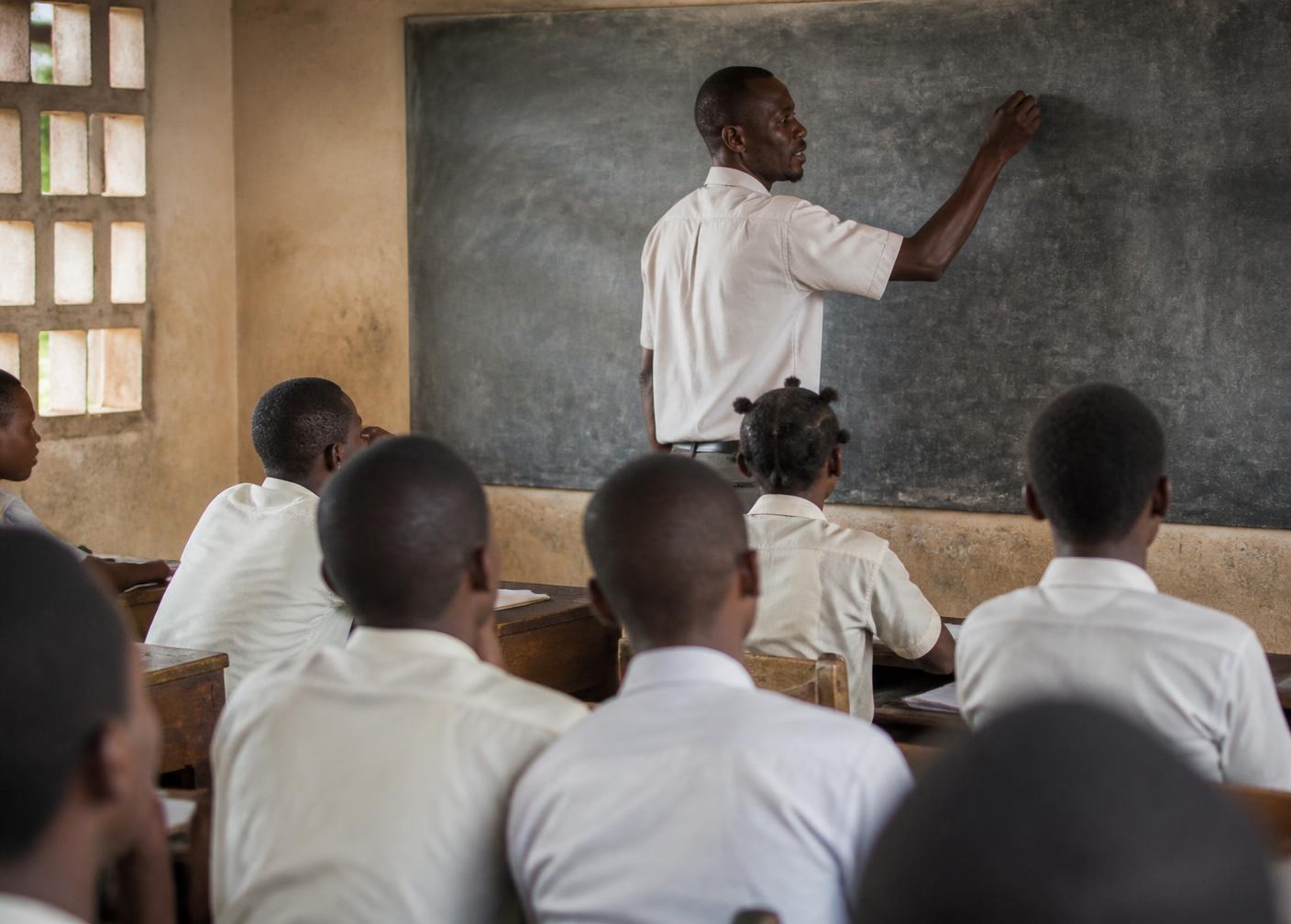 Enseignant écrivant au tableau devant sa classe